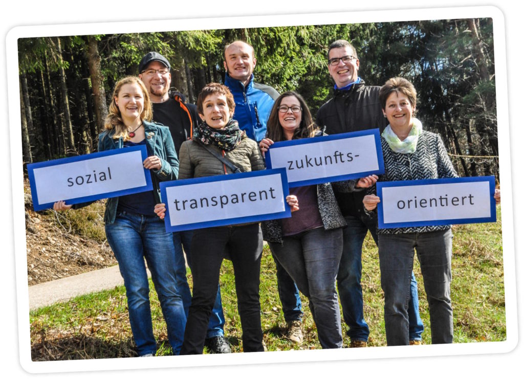Gruppenbild der Kandidierenden zur kommenden Gemeinderatswahl 2019, die den Slogan "sozial, transparent, zukunftsorientiert" auf Schildern präsentieren.